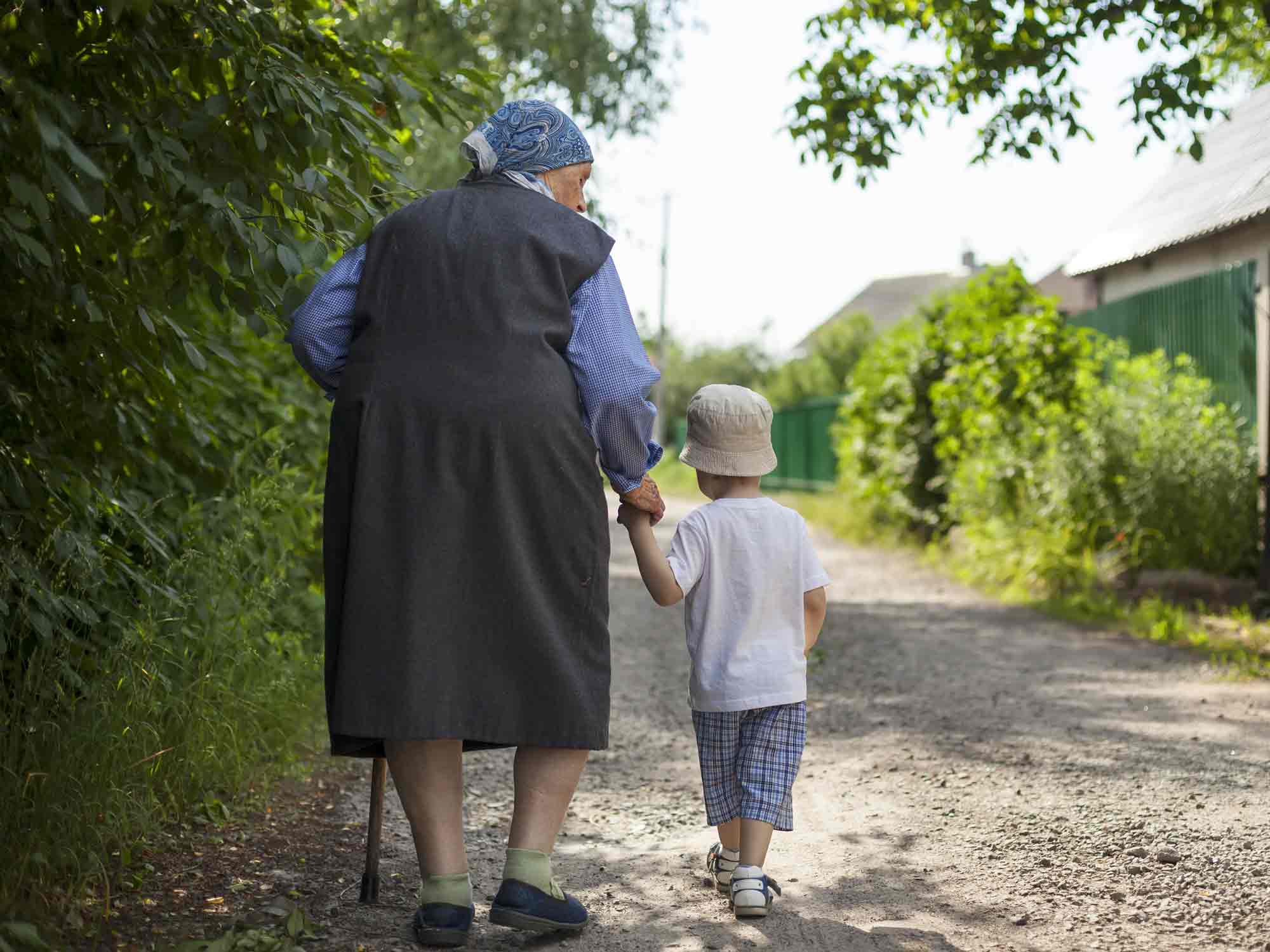 Abuela caminando junto a niño por camino en pueblo linecar